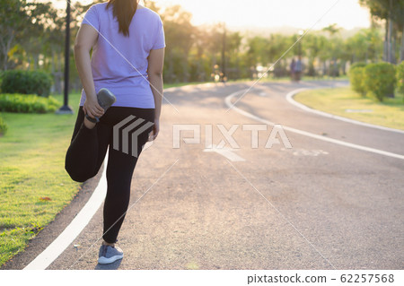 Young woman stretching her legs or quadriceps muscle before running and exercising. 62257568