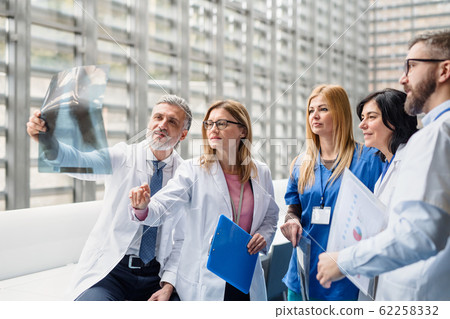 Group of doctors looking at X-ray on medical conference, discussing issues. Group of doctors looking at X-ray on medical conference, discussing issues. 62258332