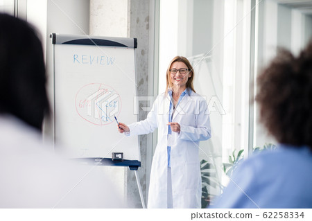 Group of doctors listening to presentation on medical conference. Group of doctors listening to presentation on medical conference. 62258334