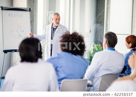 Group of doctors listening to presentation on medical conference. Group of doctors listening to presentation on medical conference. 62258337