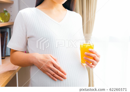 Pregnant woman drinking orange juice Pregnant woman drinking orange juice 62260371