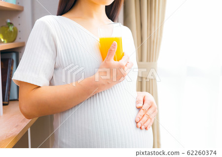 Pregnant woman drinking orange juice Pregnant woman drinking orange juice 62260374