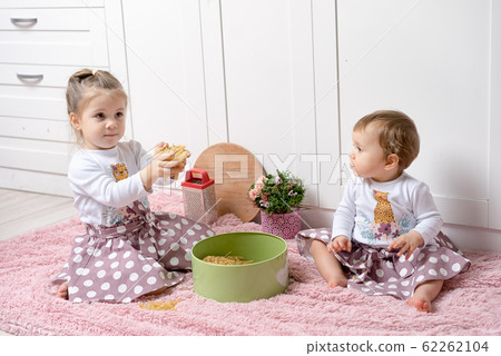 Sisters 1 and 3 years old girls sit on the floor Sisters 1 and 3 years old girls sit on the floor 62262104