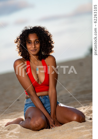 Dark-skinned girlfriend sitting on the beach in the evening Dark-skinned girlfriend sitting on the beach in the evening 62263105