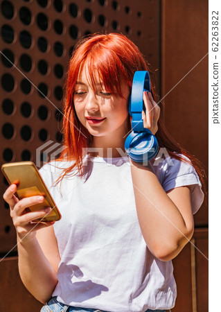 Girl listens to music putting headphones to ear 62263822