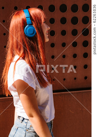 Girl listening to music on street in headphones 62263836