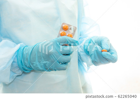 Nurse in sterile gown and gloves gives pill from pack Nurse in sterile gown and gloves gives pill from pack 62265040