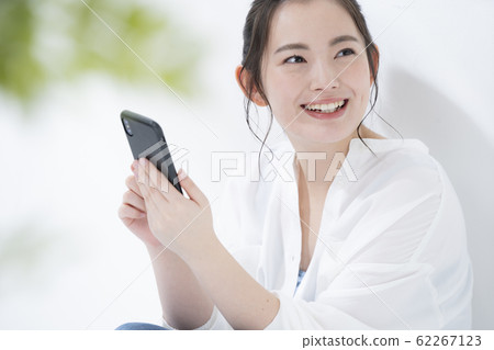A young woman operating a smartphone A young woman operating a smartphone 62267123