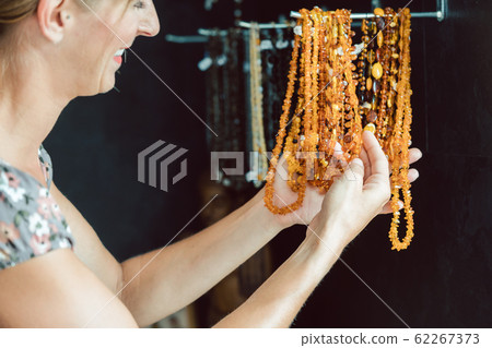 Woman looking at a necklace made of amber 62267373