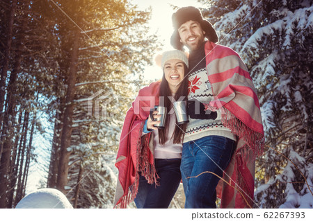 Woman and man on cold winter day warming up with hot tea 62267393