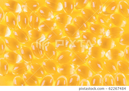 golden omega capsules on yellow background, 62267484