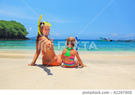 Mother, baby girl in snorkeling mask sit on sand Mother, baby girl in snorkeling mask sit on sand 62267808