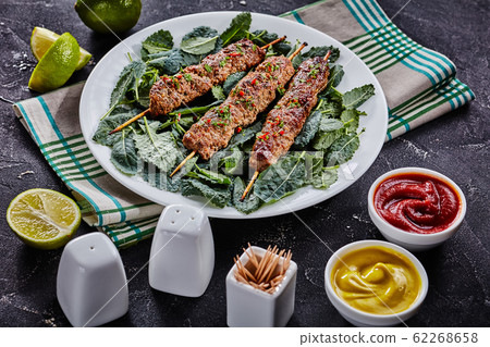 Lamb kebab on skewers, served with fresh kale 62268658