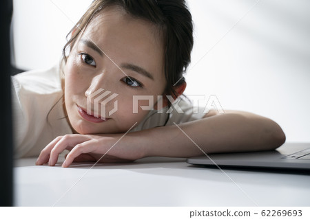 躺在桌子上同時操作智能手機的女人 躺在桌子上同時操作智能手機的女人 62269693