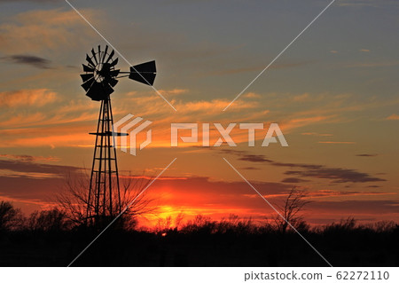 Kansas colorful Sunset with a colorful sky,tree's, and Windmill silhouettes out in the country Kansas colorful Sunset with a colorful sky,tree's, and Windmill silhouettes out in the country 62272110