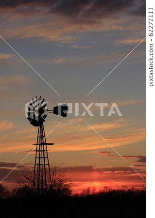 Kansas colorful Sunset with a colorful sky,tree's, and Windmill silhouettes out in the country 62272111