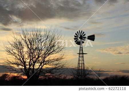 Kansas colorful Sunset with a colorful sky,tree's, and Windmill silhouettes out in the country Kansas colorful Sunset with a colorful sky,tree's, and Windmill silhouettes out in the country 62272118