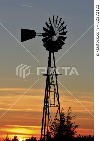 Kansas colorful Sunset with a colorful sky,tree's, and Windmill silhouettes out in the country 62272122