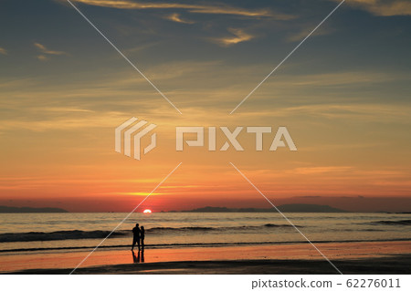 The perfect sunset ,a silhouetted couple take in the last vestiges of the day on a the beach,koh Phayam,ranong thailand 62276011