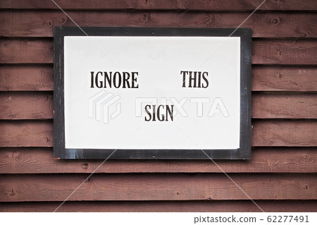 An ignore this sign on a brown wooden background 62277491