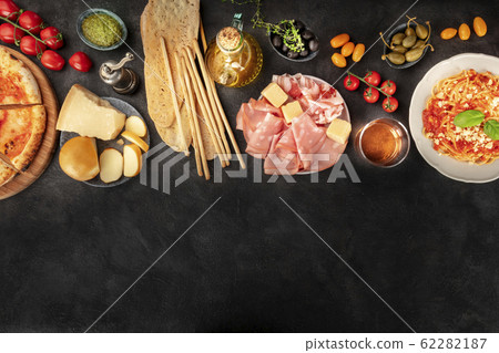 Italian food with a place for text, a flat lay design template for a restaurant. Pizza, pasta, cheese, ham, wine, olives, pesto, capers, olive oil, tomatoes, shot from the top 62282187