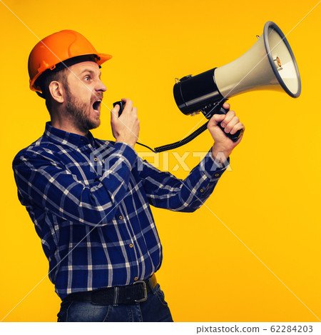 Angry worker man with a megaphone on yellow Angry worker man with a megaphone on yellow 62284203