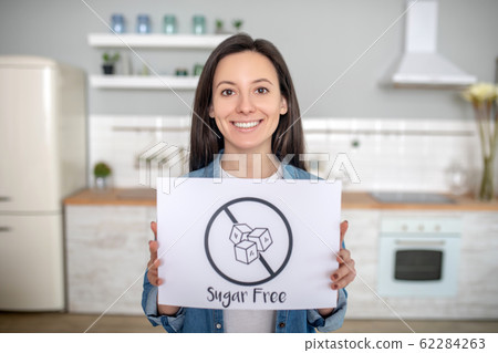 Smiling young woman holding no sugar sign 62284263