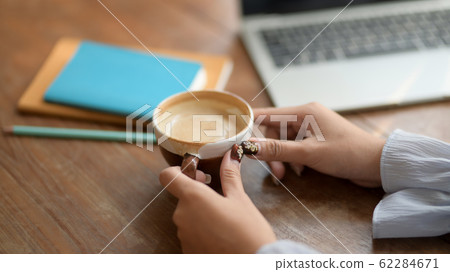 Close up view of a woman holding coffee cup in 62284671