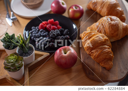 Succulents, croissants, berries, red apples on a wooden table Succulents, croissants, berries, red apples on a wooden table 62284884