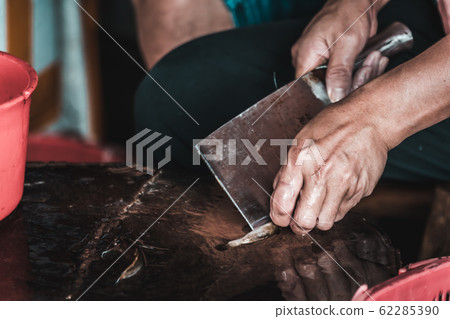 Chinese person peeling skin off small fish 62285390