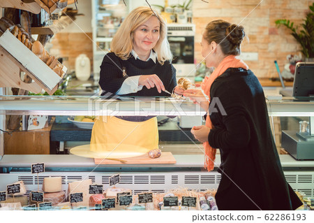 Customer and shop clerk at the cheese counter of supermarket Customer and shop clerk at the cheese counter of supermarket 62286193