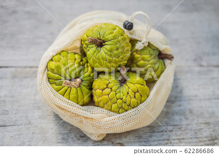 Cherimoya in a reusable bag on a stylish wooden kitchen surface. Zero waste concept, plastic free 62286686