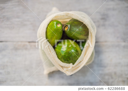 Avocado in a reusable bag on a stylish wooden kitchen surface. Zero waste concept, plastic free 62286688