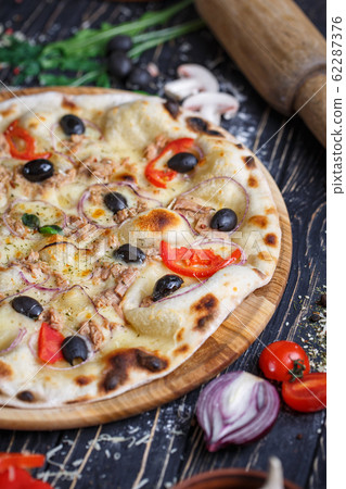 Pizza with fish, olives, onions and tomatoes near Pizza with fish, olives, onions and tomatoes near 62287376