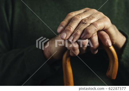 Hands of a senior man clasping a cane Hands of a senior man clasping a cane 62287377