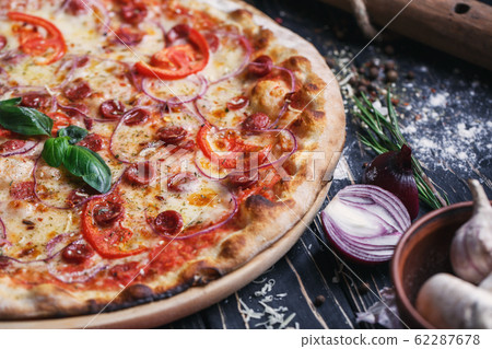Pizza with sausages, ham, onions and tomatoes Pizza with sausages, ham, onions and tomatoes 62287678