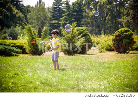 Little boy playing with his soap bubbles toy in 62288190