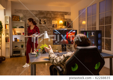 Back view of professional video gamer playing on powerful PC late at night in the living room Back view of professional video gamer playing on powerful PC late at night in the living room 62288635