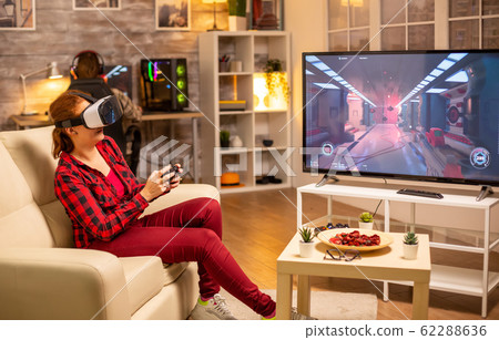Woman gamer playing video games using a VR headset late at night Woman gamer playing video games using a VR headset late at night 62288636