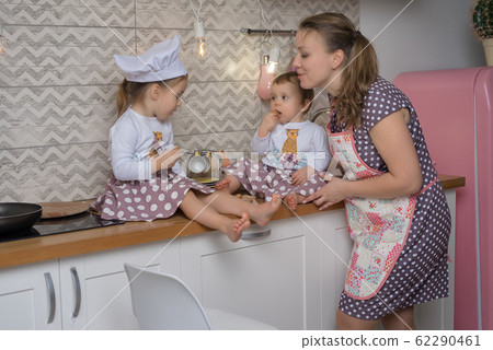 Little girls in chef hats with mother in apron is 62290461