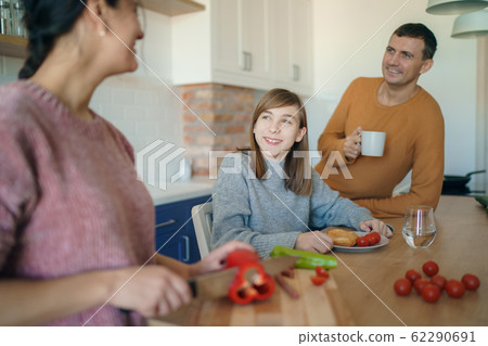 Mom, dad and daughter are cooking on kitchen. Happy family concept. Handsome man, attractive young woman and their cute little daughter are making food together. Healthy lifestyle. 62290691