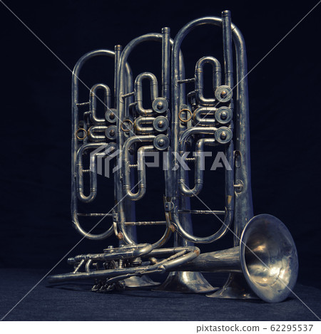 Four old brass wind instrument stand on a table 62295537
