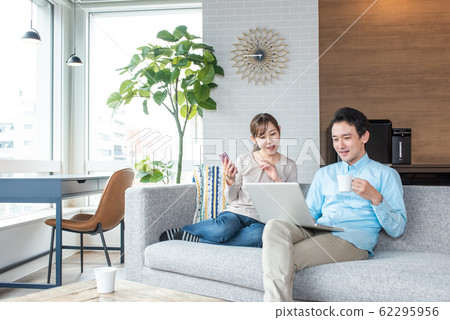 Young couple talking while looking into a personal computer in the living room 62295956