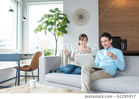 Young couple talking while looking into a personal computer in the living room 62295957