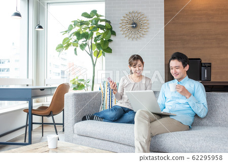 Young couple talking while looking into a personal computer in the living room 62295958