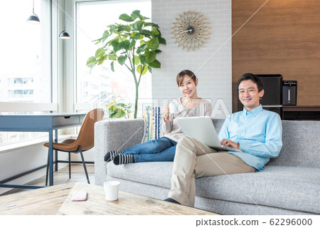 Young couple talking while looking into a personal computer in the living room Young couple talking while looking into a personal computer in the living room 62296000