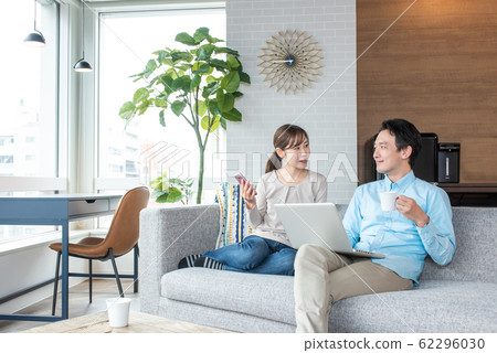 Young couple talking while looking into a personal computer in the living room Young couple talking while looking into a personal computer in the living room 62296030