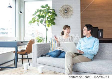 Young couple talking while looking into a personal computer in the living room Young couple talking while looking into a personal computer in the living room 62296031