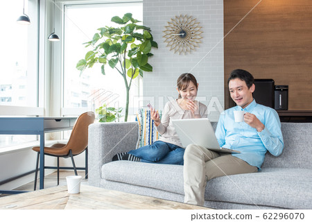 Young couple talking while looking into a personal computer in the living room Young couple talking while looking into a personal computer in the living room 62296070