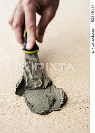 man spreading some concrete on a surface man spreading some concrete on a surface 62296152